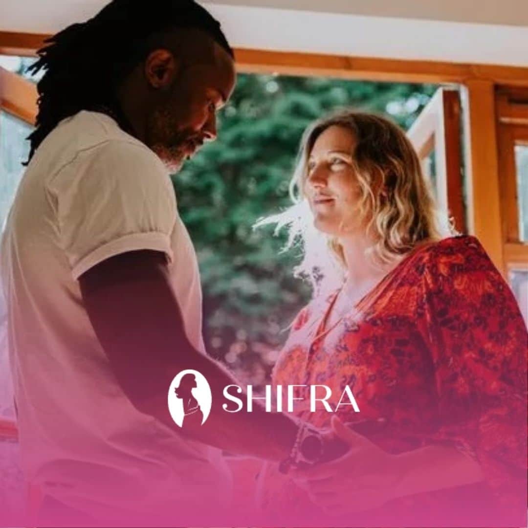 A man and pregnant woman holding hands and smiling near window, easing their fear of parenthood.