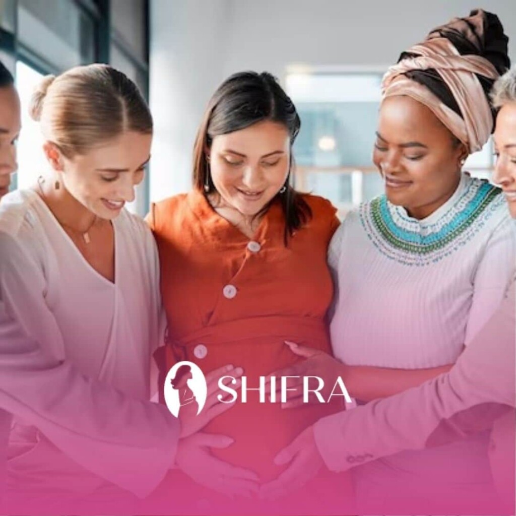 Supportive women in an office smiling and touching a pregnant woman’s belly, expressing support.