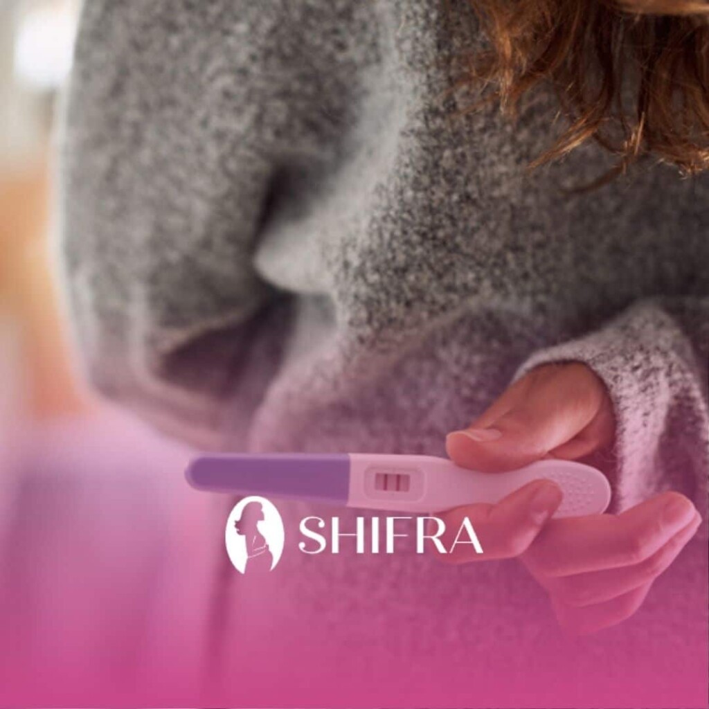 A worried jewish woman in a sweater holding a positive pregnancy test with two lines visible.